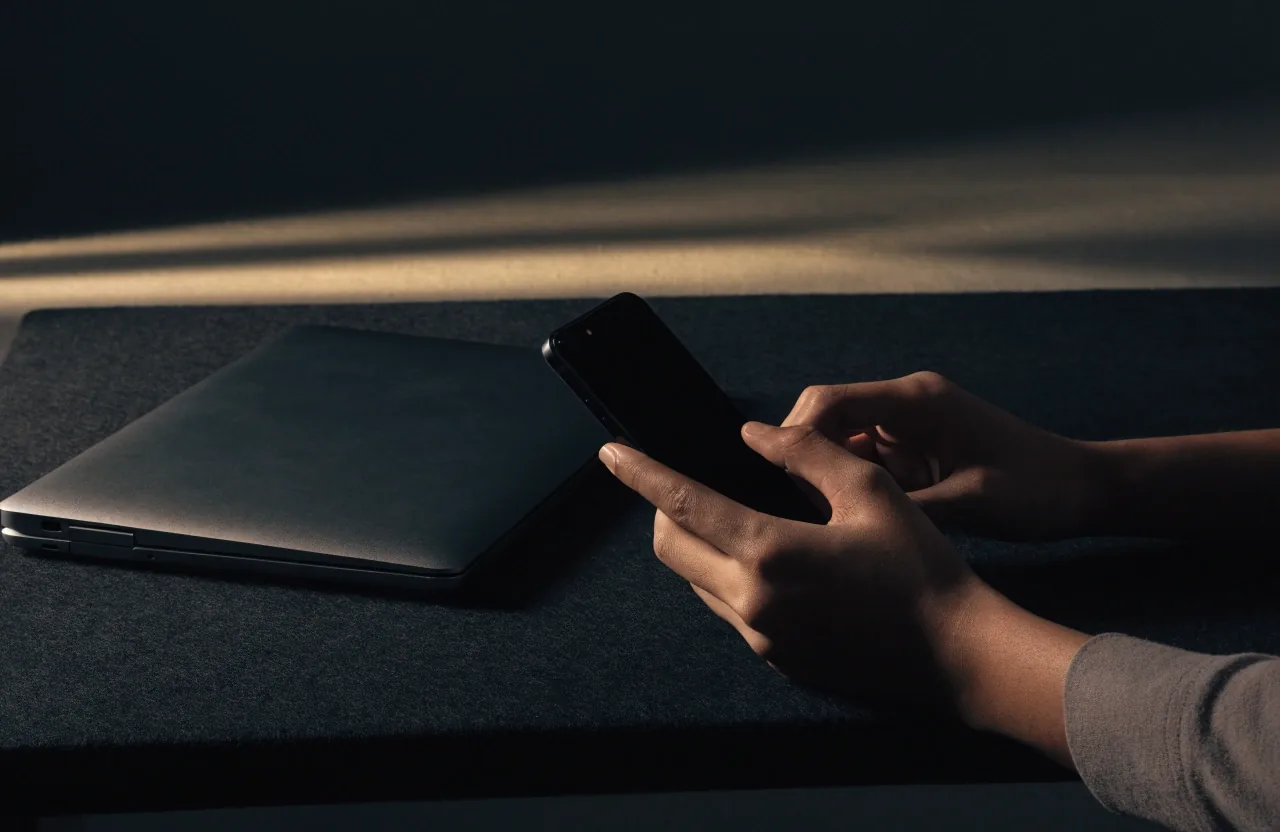 Duova LLC studio table with a laptop and phone set on charcoal felt under soft shadowless light